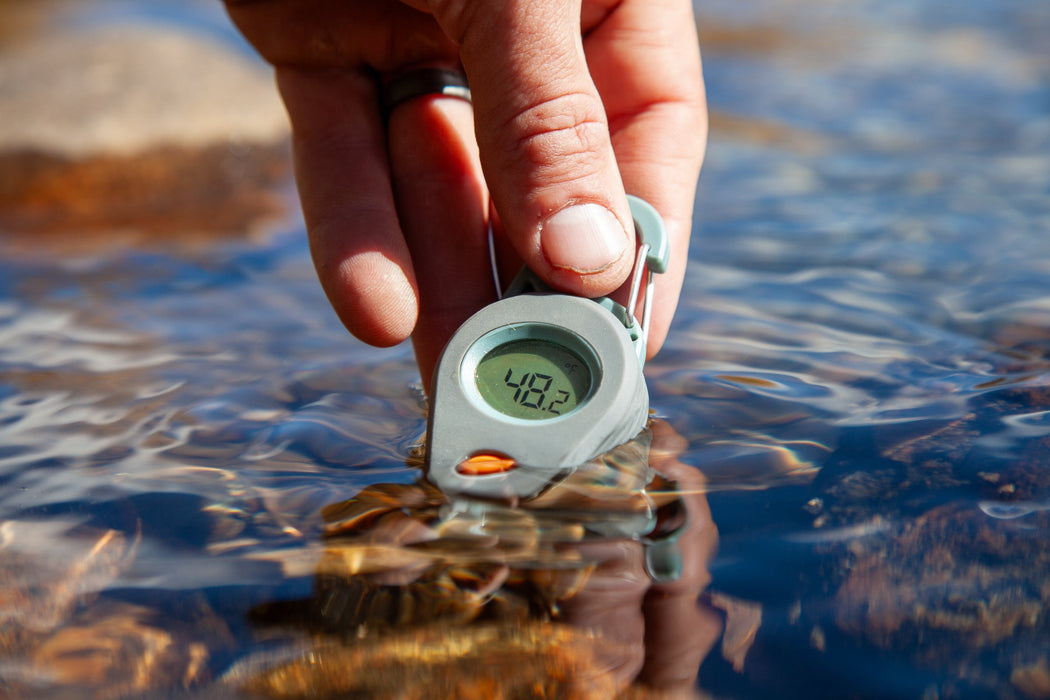 a fishpond riverkeeper thermometer being dipped in a stream 