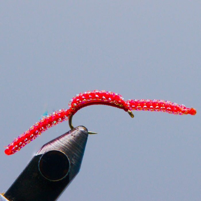 A red Sparkle San Juan Worm tied in Rangeley Maine