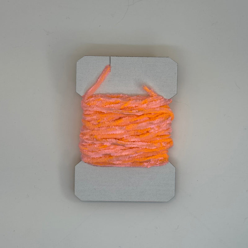 Chenille yarn bundle in bright orange, tightly looped with yarn tail visible