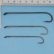 Set of three streamer fishing hooks with dark wire, sized against a ruler