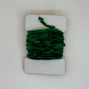 Chenille yarn bundle in dark green, tightly looped with yarn tail visible