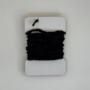 Chenille yarn bundle in black, tightly looped with yarn tail visible