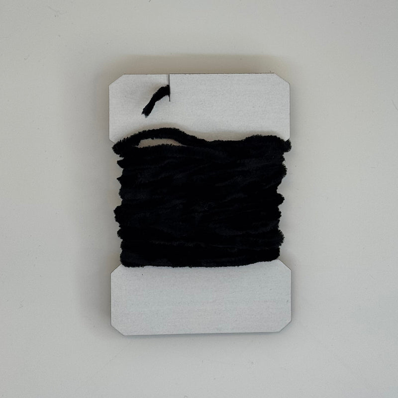 Chenille yarn bundle in black, tightly looped with yarn tail visible