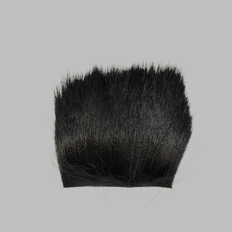 Black deer hair patch with dense dark fibers and trimmed base edge