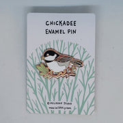 Chickadee enamel pin with bird design on a backing card.