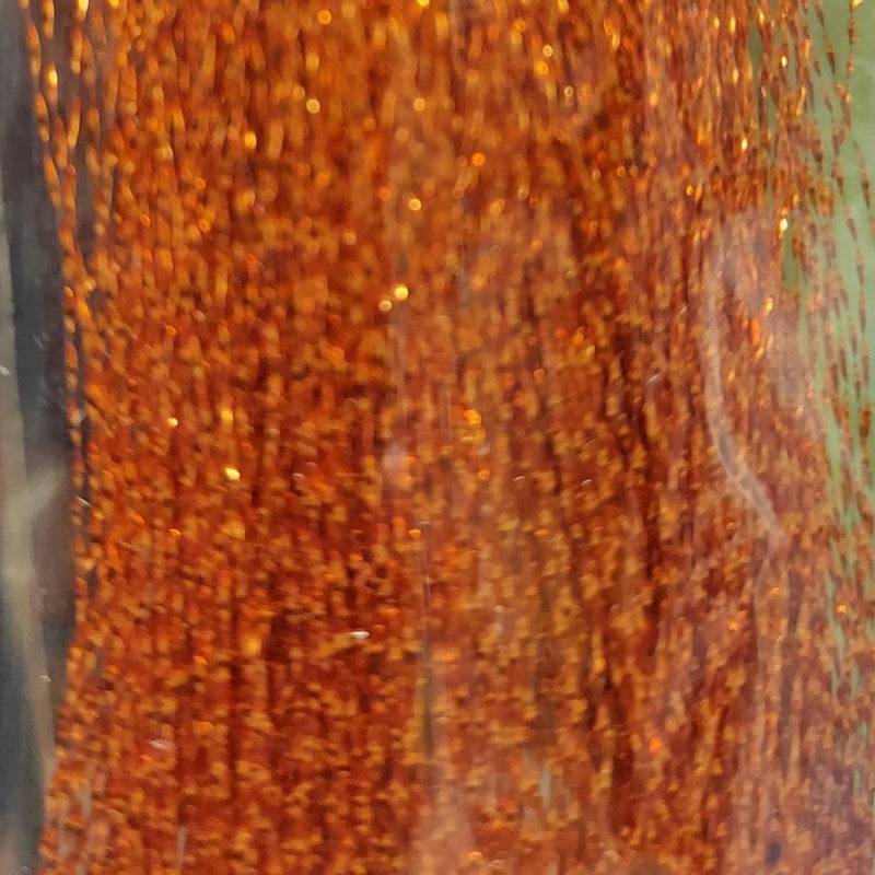 Orange sparkly tinsel fibers with warm gold glitter