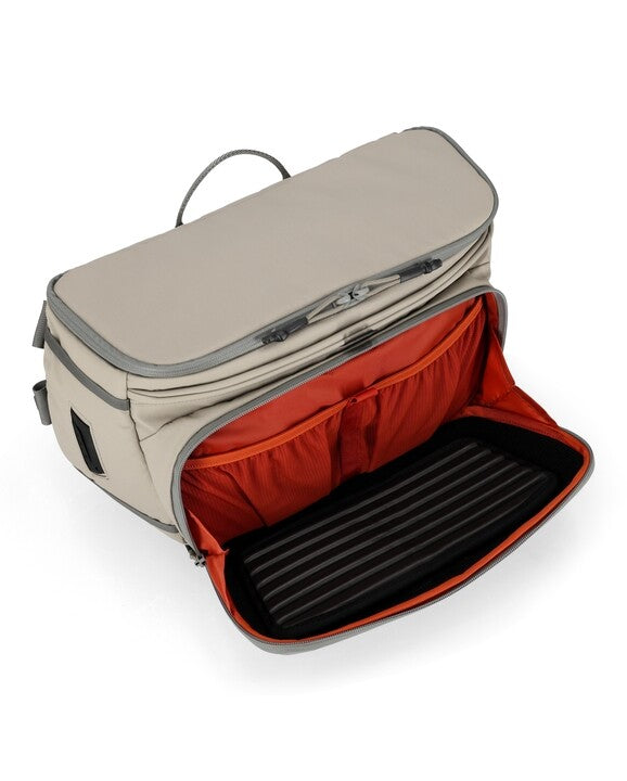 Simms sling pack opened, beige exterior with red interior compartment and divider