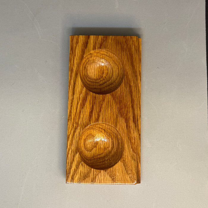 a small wooden square with two round depressions used by fly tyers to hold beads, hooks, and other small items