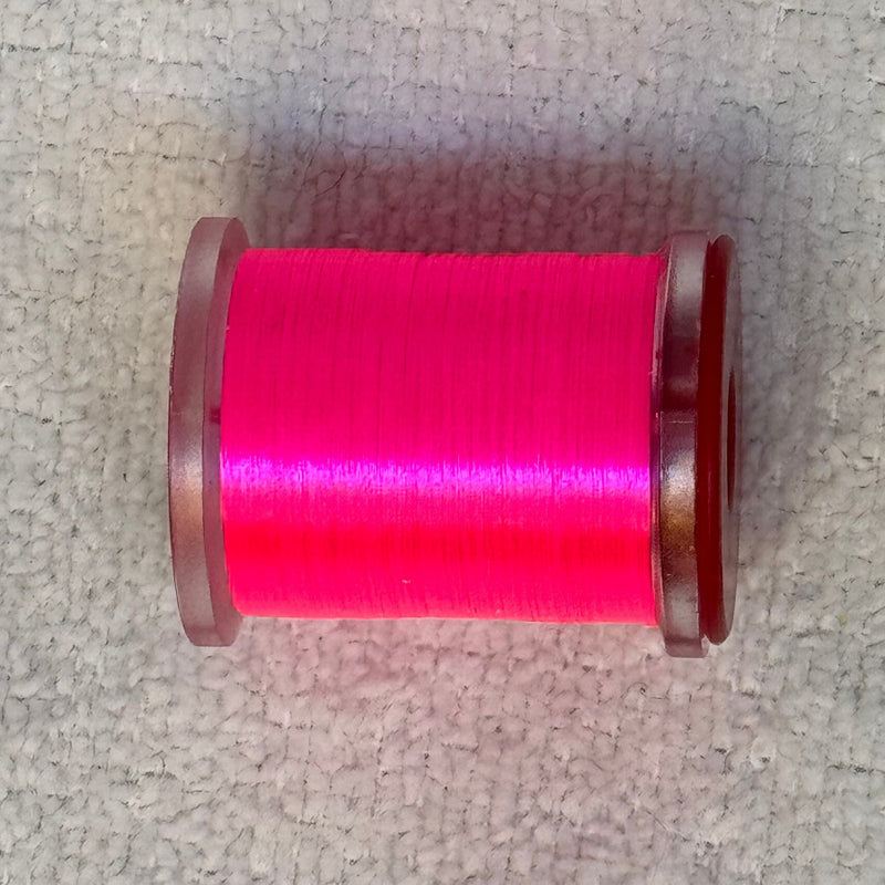 70 denier thread spool in hot pink on a light fabric surface