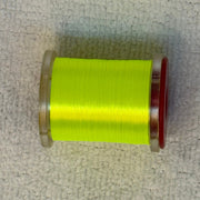 70 denier thread spool in neon green on a light fabric surface