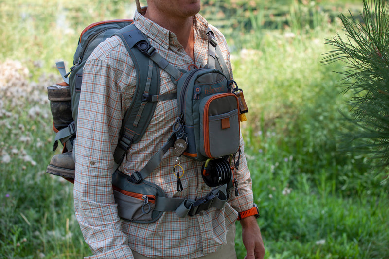 Fishpond Firehole backpack on a person, dark gray with orange trim and waist belt