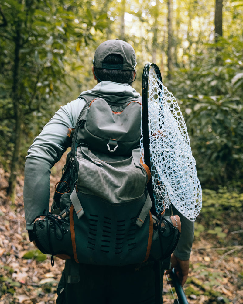 Fishpond Firehole backpack on a person, dark gray with orange accents and mesh pocket