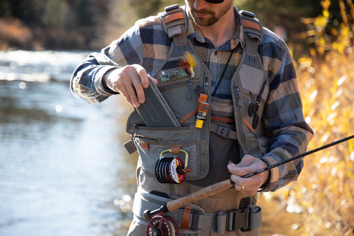 Fly fishing vest worn with multiple zip pockets and belt loops, gray with orange trim
