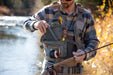 a male angler retrieving a fly box from the pocket of his Fishpond Flint Hills Fly Fishing Vest