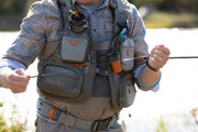 Mesh fishing vest worn on torso with gray utility pockets and orange accent tabs