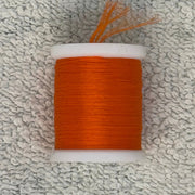 Four-strand floss spool with rust orange thread on a white core