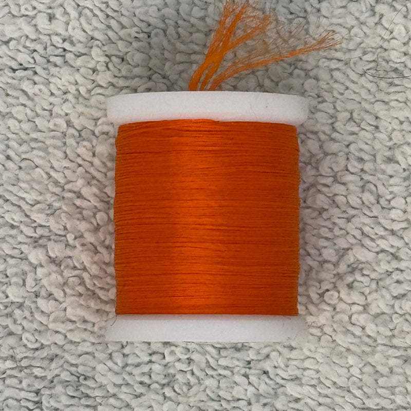 Four-strand floss spool with rust orange thread on a white core