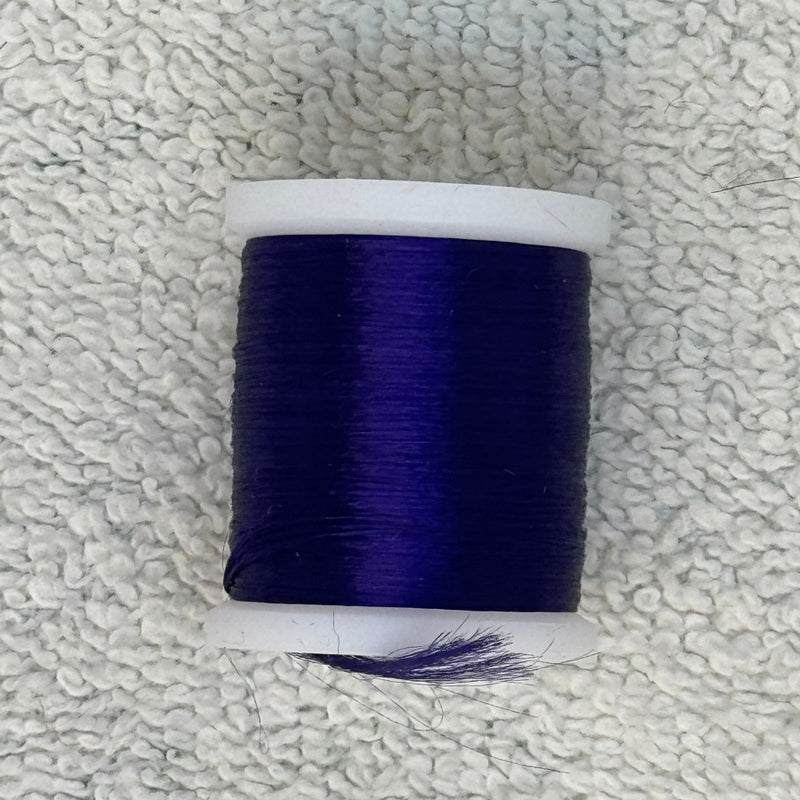 Four-strand floss spool in deep navy blue with loose thread
