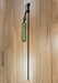 A REC brand wading staff extended and its olive sheath with a black handle and retractor, lying on a light brown wooden floor. The REC logo is clearly visible on both the sheath and the retractor.