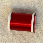 70 denier thread spool in red on a light fabric surface