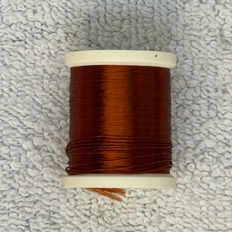 Four-strand floss spool with reddish brown thread on a cream core