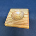 a small wooden square with a round depression used by fly tyers to hold beads, hooks, and other small items