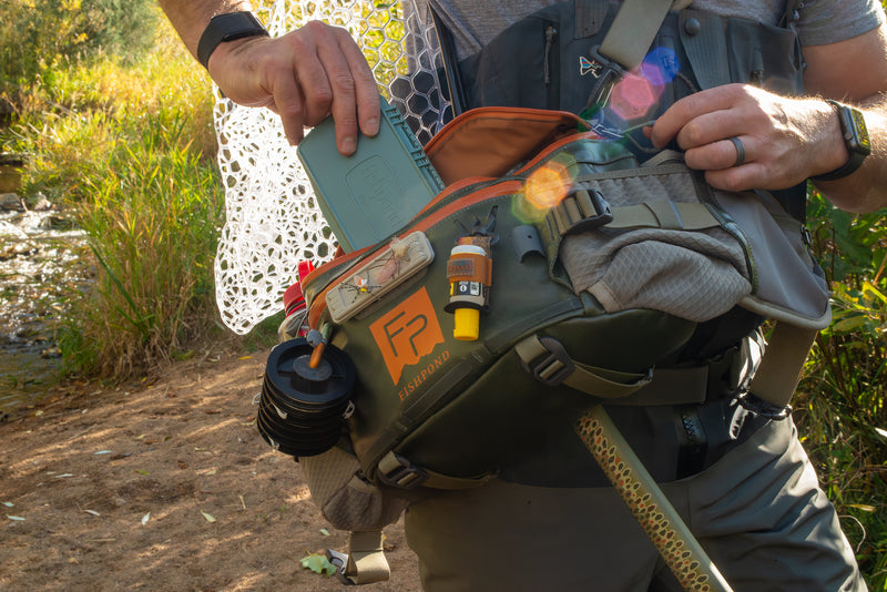Lumbar pack worn with open top pouch, orange interior, bottles and gear