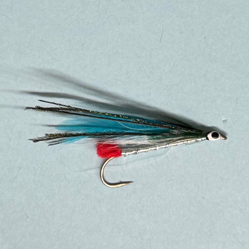 Fishing lure with teal and black feather tail and red-tied hook, silver head