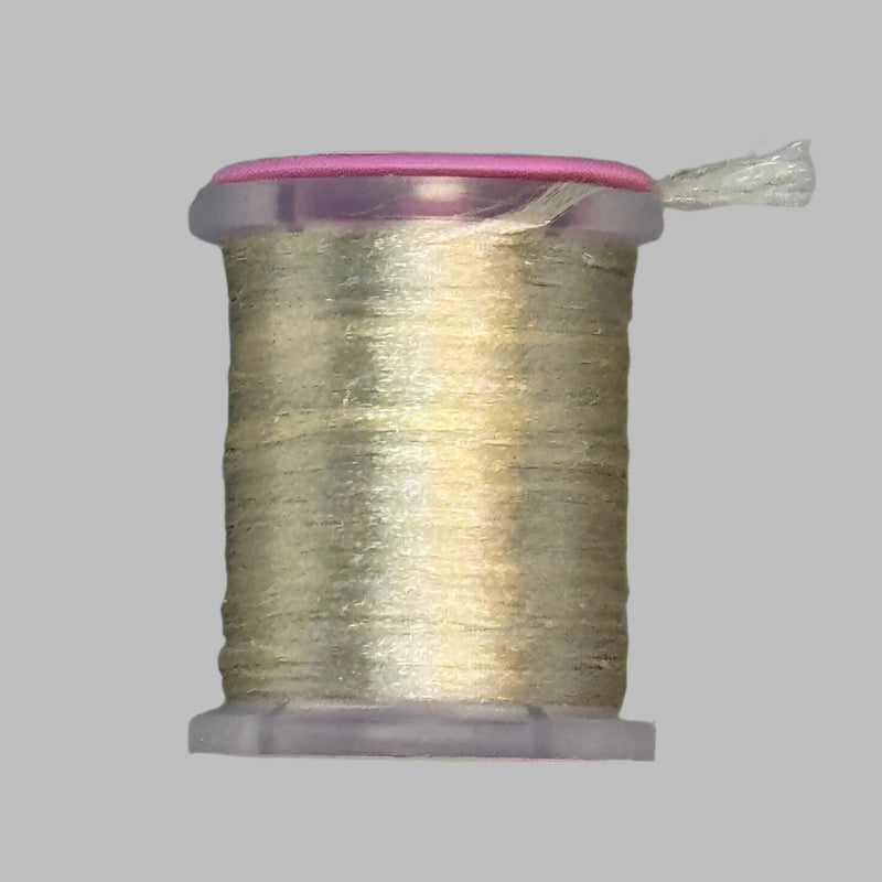 UTC Antron yarn spool in light gold with loose thread end above the bobbin