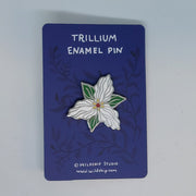 Trillium enamel pin with white flower design on a backing card.