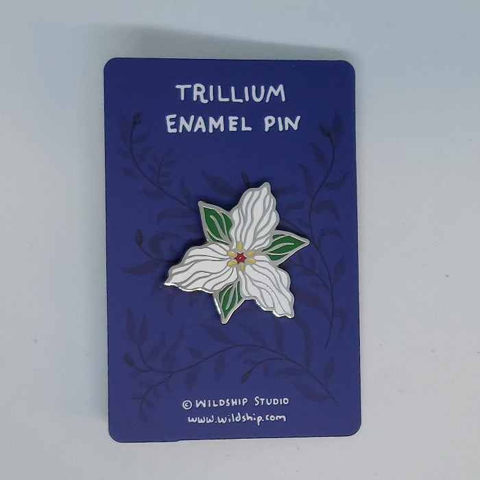 Trillium enamel pin with white flower design on a backing card.