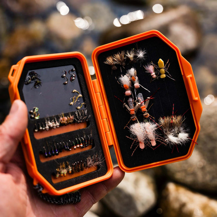 a hand holding an open atollas micro fly box with flies on both magnetic and foam surfaces