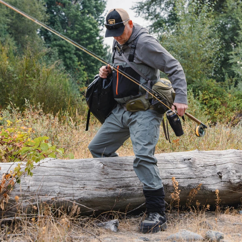 Men's stockingfoot waders worn in outdoor setting, gray legs with black boots and orange trim