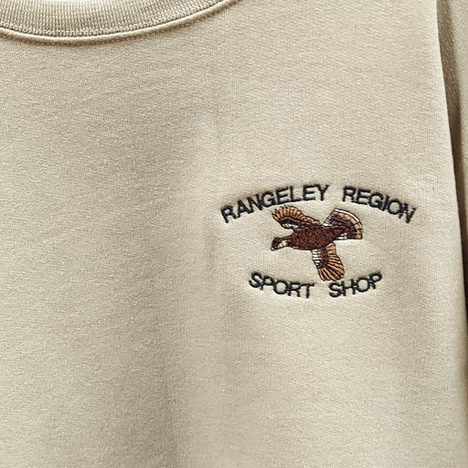 close up of the flying grouse and shop name design on a tan sweatshirt