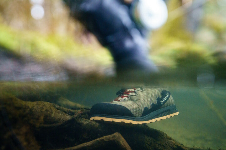 Dark camo wading boot with brown laces and SIMMS logo, black sole