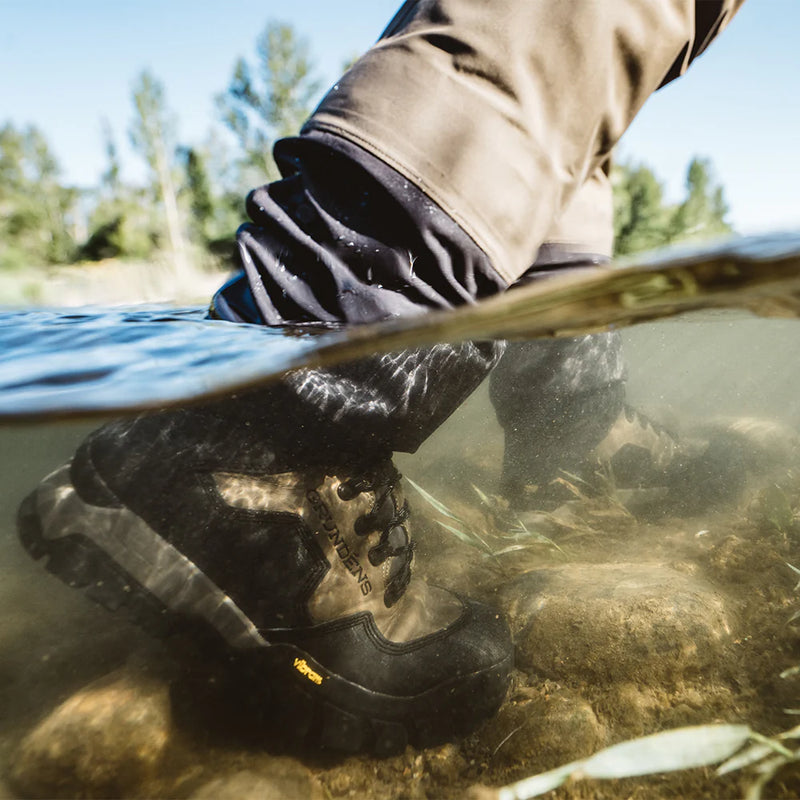 Water wading boot on foot partially submerged, showing rubber sole and tread