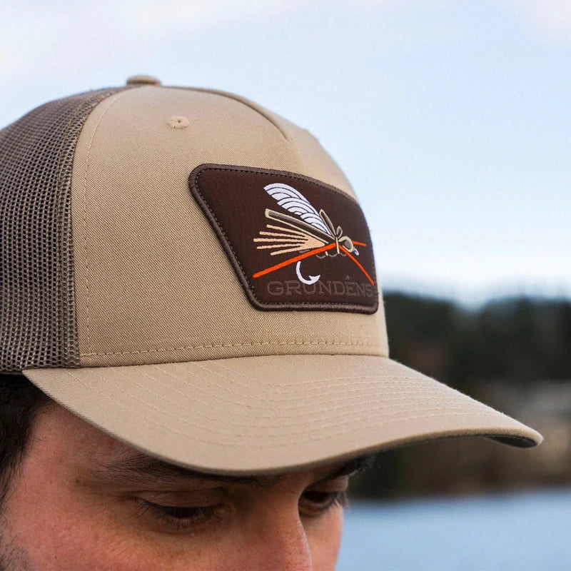Pale khaki trucker cap with mesh side panels and embroidered logo patch
