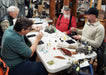 People working on tying flies in a store with various gear displayed.