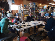 Tying lessons workshop group at workbenches with supplies and crafting tools