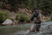 Sling pack on angler’s back with straps and front zipper pocket