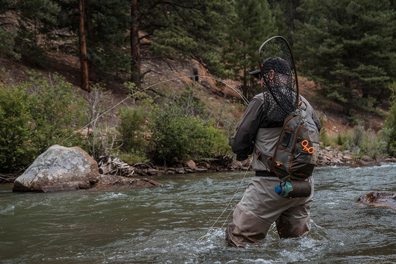 Sling pack on angler’s back with straps and front zipper pocket