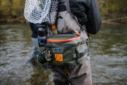Lumbar pack worn with orange-edged pocket and camera lens pouch