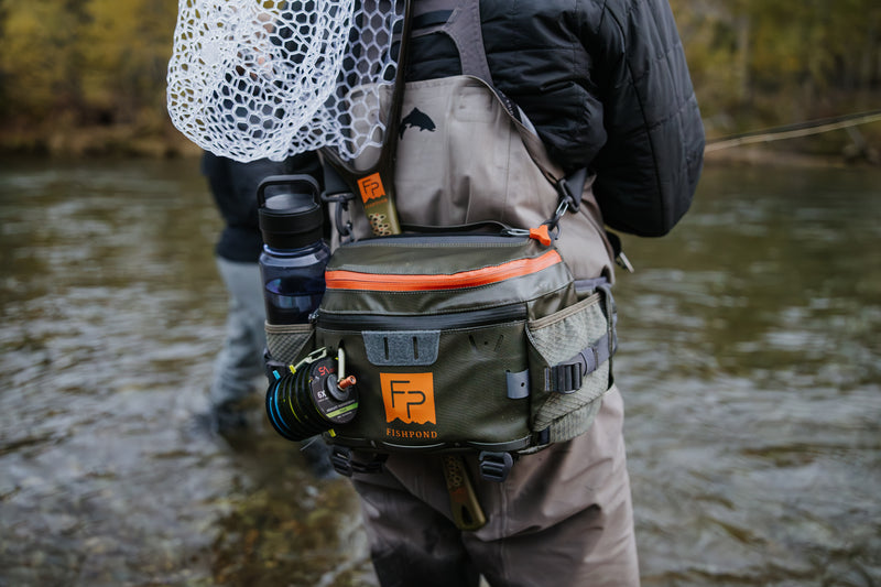 Lumbar pack worn with orange-edged pocket and camera lens pouch