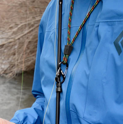 Person wearing a blue jacket with a fishing rod held by a holder attached to a lanyard