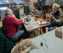 Group of people gathered around a table in a store tying flies.