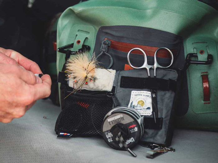 Utility pack with green outer and black pouch, tools and scissors, white fur patch
