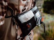 Utility pack with black zip pouch and white fur patch, attached to camo clothing