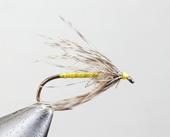 Partridge and Yellow fishing fly with yellow body and white-brown feather wings