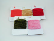 Rayon chenille yarn spools in red, tan, dark olive, and pink on a display card