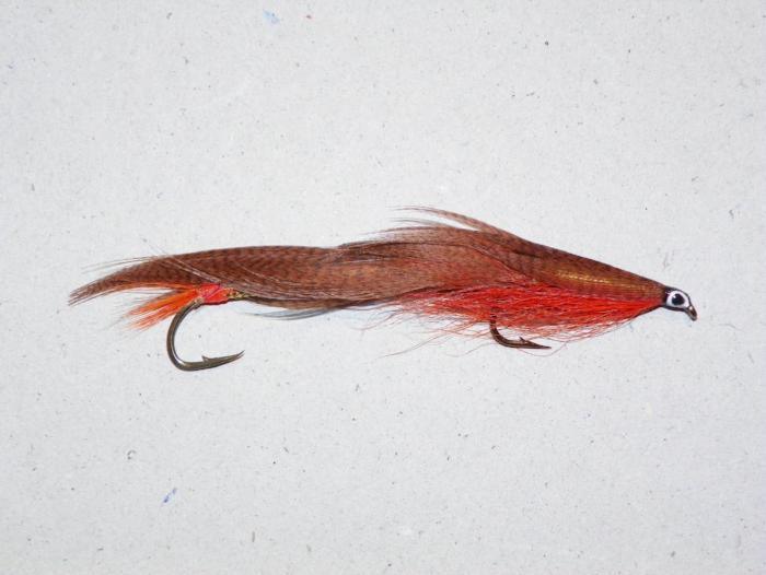 Fishing lure with red and brown body, feather tail, and two treble hooks